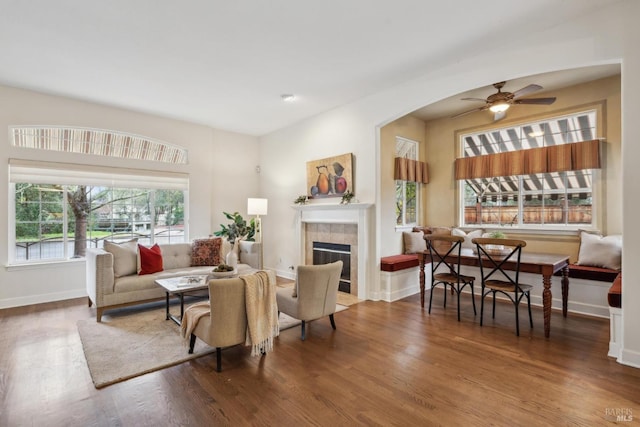 living room with hardwood / wood-style flooring, a tile fireplace, and ceiling fan