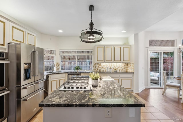 kitchen featuring hanging light fixtures, appliances with stainless steel finishes, a center island, and cream cabinets