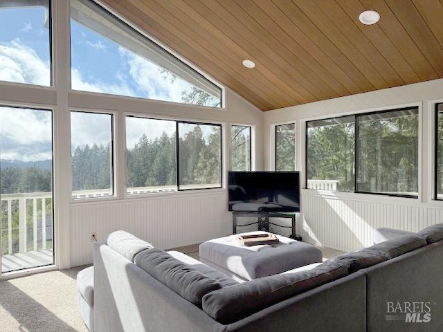 living room with vaulted ceiling, plenty of natural light, carpet floors, and wood ceiling