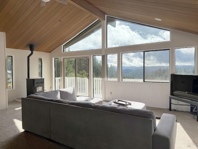 living area with vaulted ceiling with beams, carpet floors, wood ceiling, and a wood stove