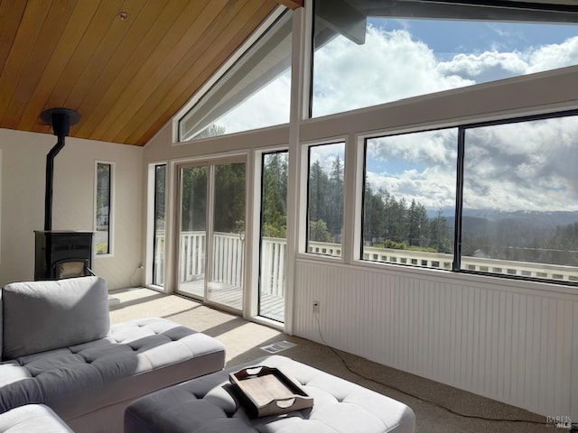 sunroom / solarium featuring a wood stove, wooden ceiling, visible vents, and vaulted ceiling