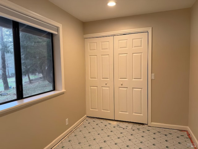 unfurnished bedroom with light floors, multiple windows, and baseboards