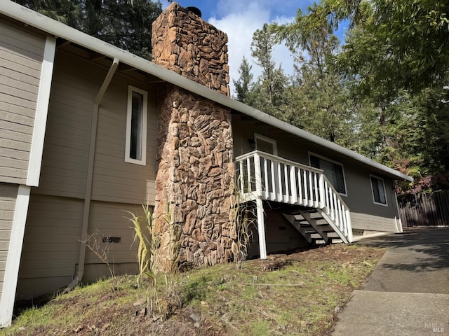 view of side of home with stairs, stone siding, crawl space, and a chimney