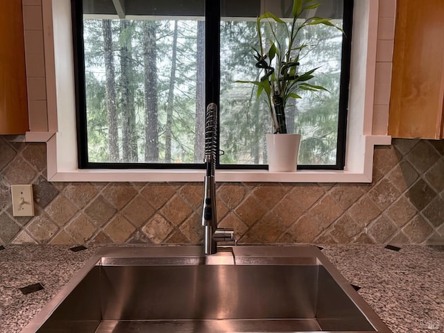 interior details featuring a sink, decorative backsplash, and light stone countertops