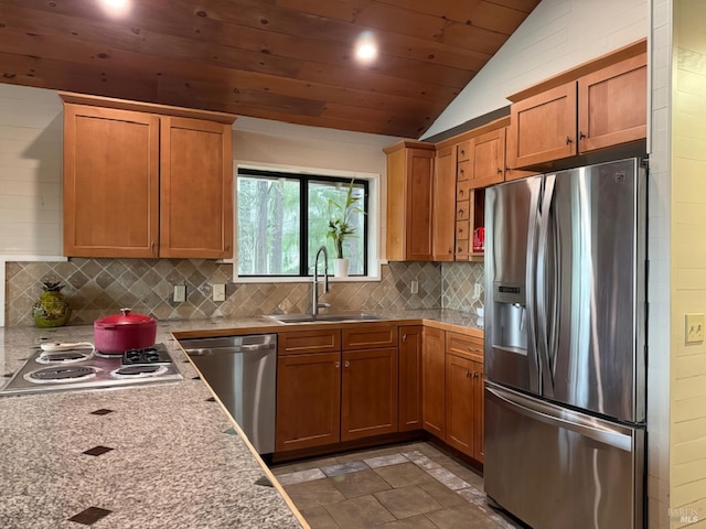 kitchen featuring decorative backsplash, vaulted ceiling, stainless steel appliances, light countertops, and a sink