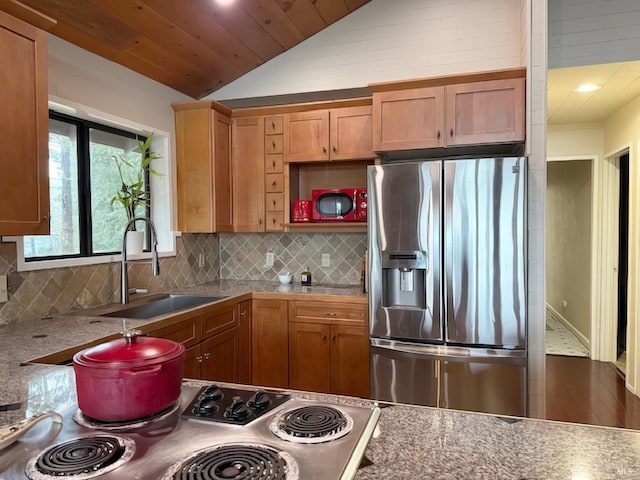 kitchen with range, decorative backsplash, stainless steel fridge with ice dispenser, vaulted ceiling, and a sink