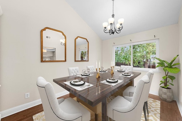 dining room with baseboards, visible vents, wood finished floors, vaulted ceiling, and a chandelier