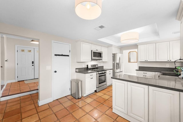 kitchen featuring stainless steel appliances, visible vents, white cabinetry, dark countertops, and a raised ceiling