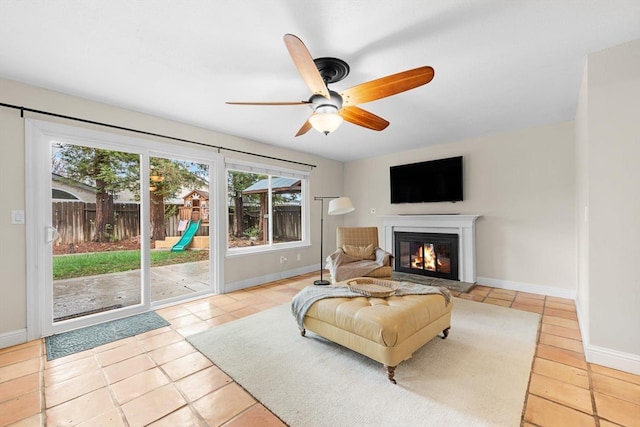 sitting room featuring a glass covered fireplace, ceiling fan, and baseboards