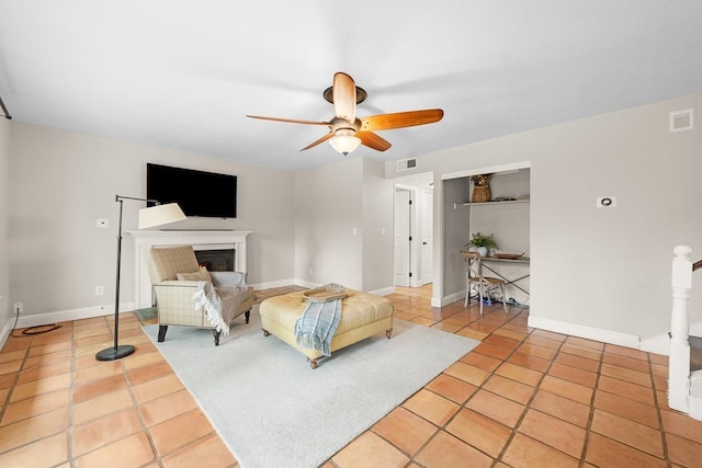 bedroom featuring a warm lit fireplace, baseboards, visible vents, ceiling fan, and light tile patterned flooring