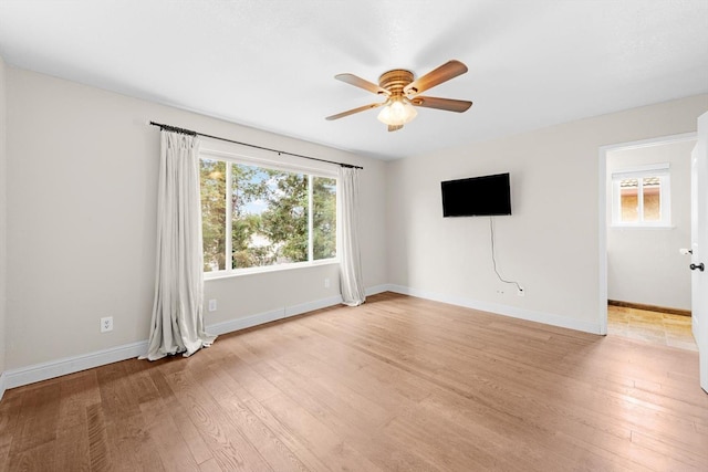 unfurnished living room with light wood finished floors, baseboards, and a ceiling fan