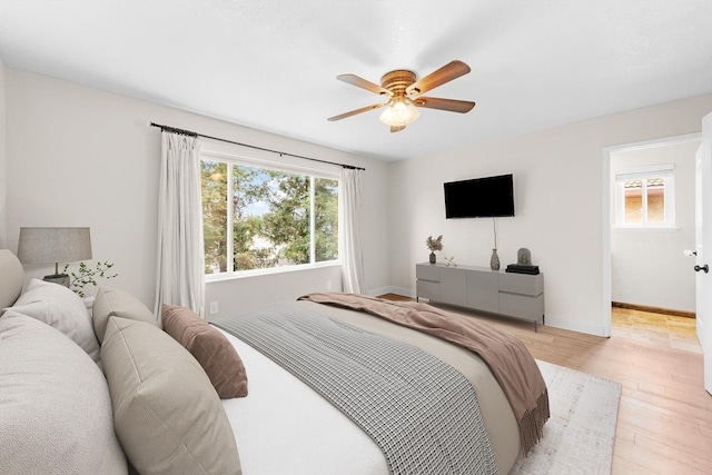 bedroom with light wood-style floors, baseboards, and a ceiling fan