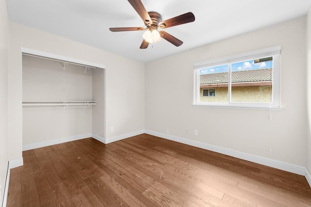 unfurnished bedroom with a closet, wood-type flooring, baseboards, and a ceiling fan