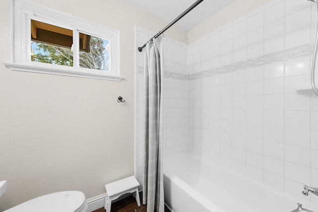 bathroom featuring toilet, baseboards, and shower / bath combination with curtain