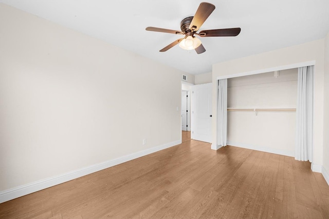 unfurnished bedroom featuring baseboards, visible vents, ceiling fan, wood finished floors, and a closet