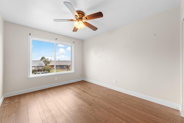 empty room with wood finished floors, a ceiling fan, and baseboards