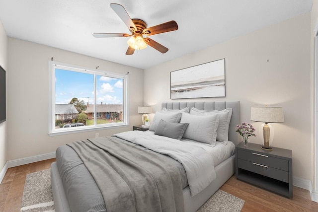 bedroom featuring ceiling fan, baseboards, and wood finished floors