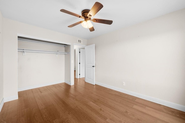 unfurnished bedroom featuring a closet, visible vents, baseboards, and wood finished floors