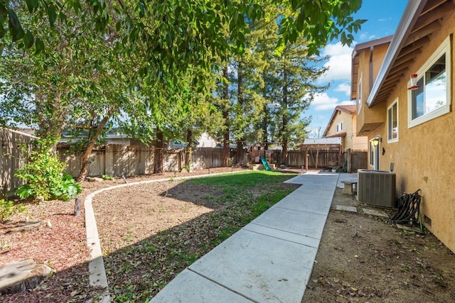 view of yard featuring central AC, a playground, and a fenced backyard