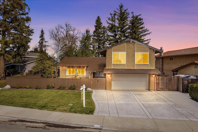 tri-level home featuring a fenced front yard, driveway, an attached garage, and a lawn