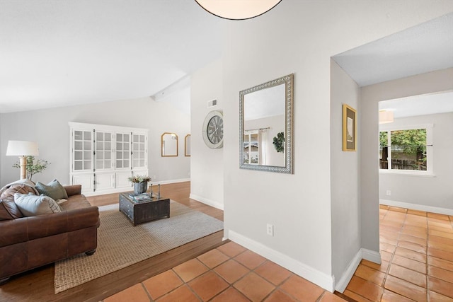 living area with vaulted ceiling with beams, tile patterned floors, visible vents, and baseboards