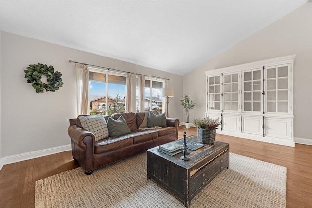 living room featuring lofted ceiling, light wood-style flooring, and baseboards