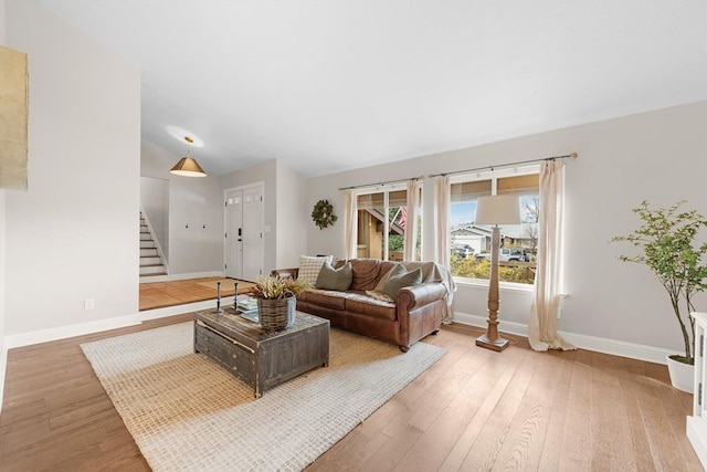 living area featuring baseboards, stairway, vaulted ceiling, and wood finished floors