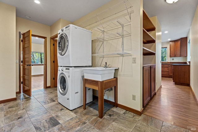 laundry room featuring stacked washing maching and dryer and sink