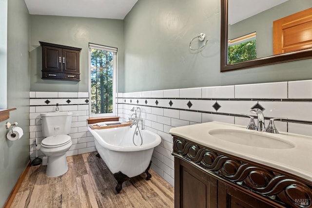 bathroom featuring toilet, a wealth of natural light, hardwood / wood-style floors, and a tub