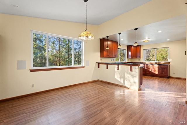 kitchen featuring a kitchen breakfast bar, kitchen peninsula, hardwood / wood-style floors, and hanging light fixtures