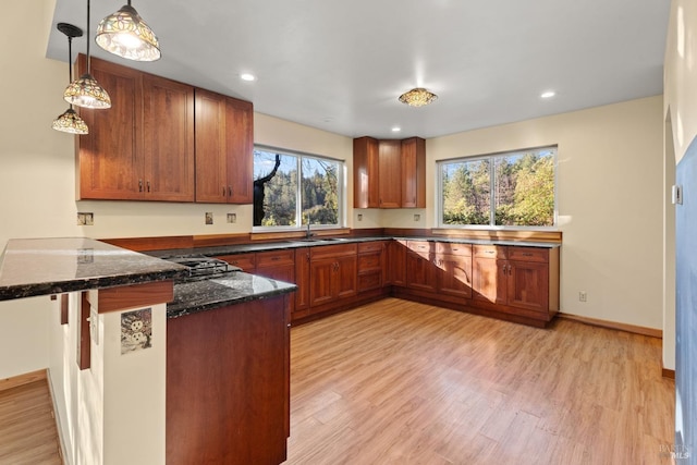 kitchen featuring sink, pendant lighting, light hardwood / wood-style floors, and kitchen peninsula