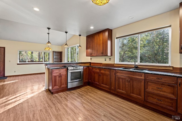 kitchen featuring sink, light wood-type flooring, stainless steel range with gas cooktop, kitchen peninsula, and pendant lighting