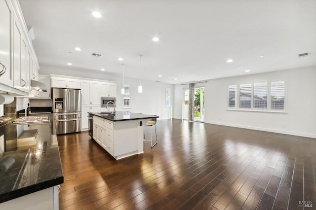 kitchen with stainless steel refrigerator with ice dispenser, white cabinetry, dark hardwood / wood-style floors, pendant lighting, and a kitchen island with sink