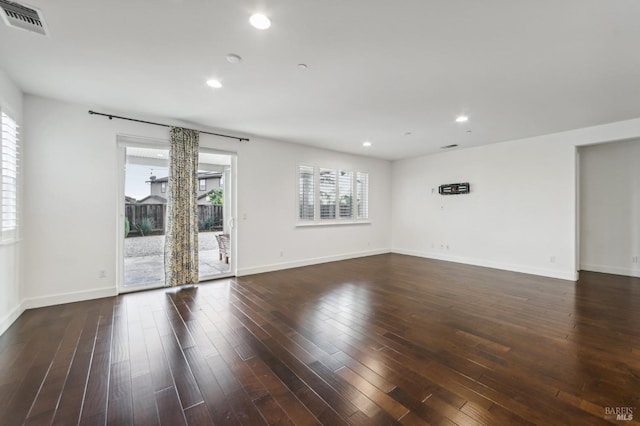 spare room with dark wood-type flooring and a healthy amount of sunlight