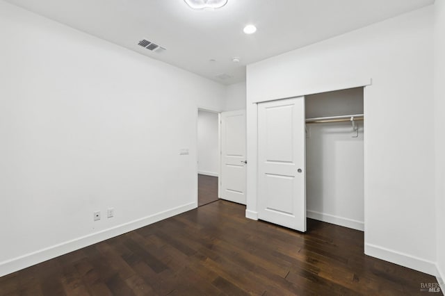 unfurnished bedroom featuring dark hardwood / wood-style flooring and a closet