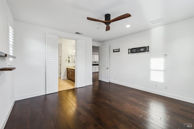 unfurnished bedroom featuring multiple windows, wood-type flooring, connected bathroom, and ceiling fan