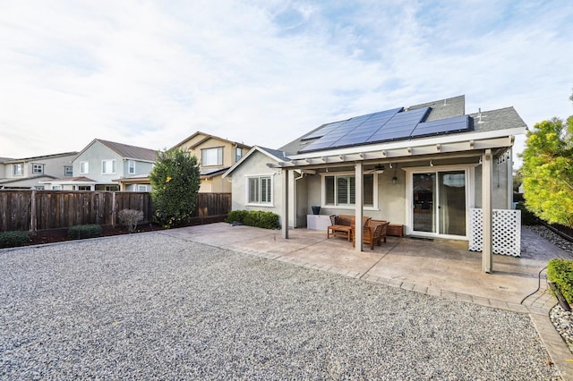 rear view of house featuring an outdoor living space, a patio, and solar panels