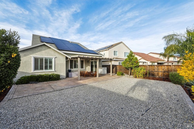 rear view of house featuring a patio area and solar panels