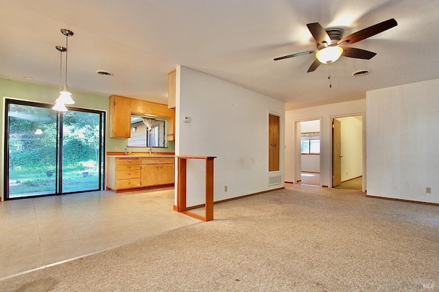 unfurnished living room featuring ceiling fan, visible vents, baseboards, and light colored carpet