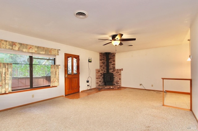 unfurnished living room with a wood stove, carpet, visible vents, and baseboards