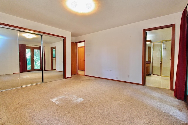 unfurnished bedroom with french doors, a closet, carpet flooring, ensuite bath, and baseboards