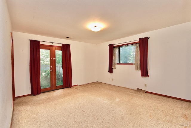 empty room with french doors, carpet flooring, visible vents, and baseboards