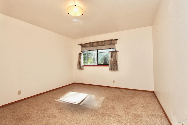 carpeted empty room featuring baseboards