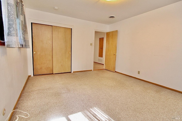 unfurnished bedroom with baseboards, a closet, visible vents, and carpet flooring