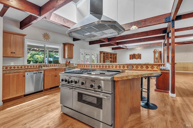 kitchen featuring appliances with stainless steel finishes, light wood-style floors, beamed ceiling, a kitchen bar, and extractor fan