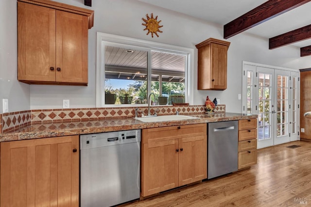 kitchen featuring a sink, light wood finished floors, stainless steel dishwasher, and beamed ceiling