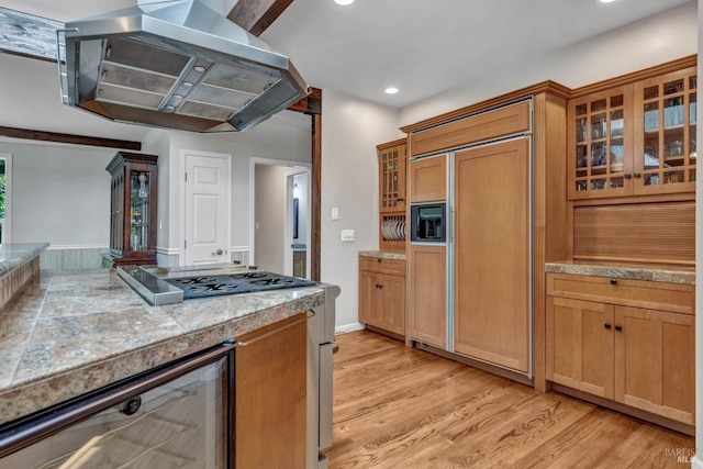 kitchen with light wood-style flooring, glass insert cabinets, paneled built in refrigerator, beverage cooler, and extractor fan