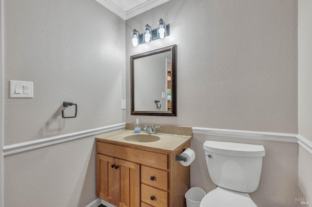 bathroom with toilet, a textured wall, vanity, and crown molding