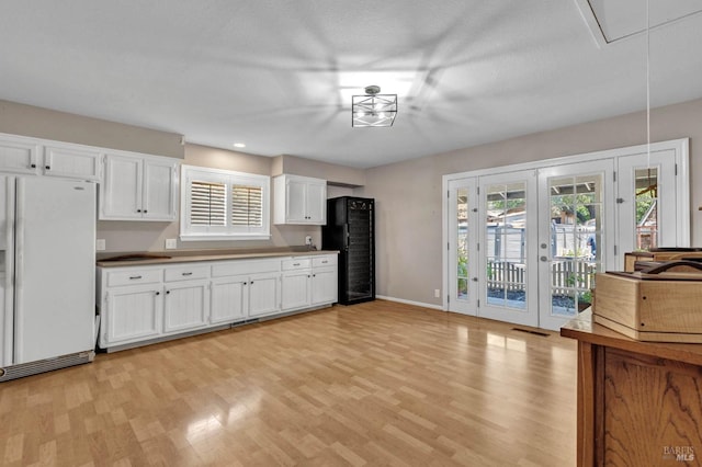 kitchen featuring light wood-type flooring, freestanding refrigerator, a healthy amount of sunlight, and white cabinets