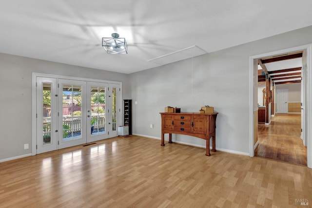 interior space with light wood-type flooring, french doors, visible vents, and baseboards